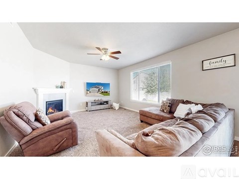A living room with a brown leather chair, a grey sofa, a fireplace, and a painting on the wall.