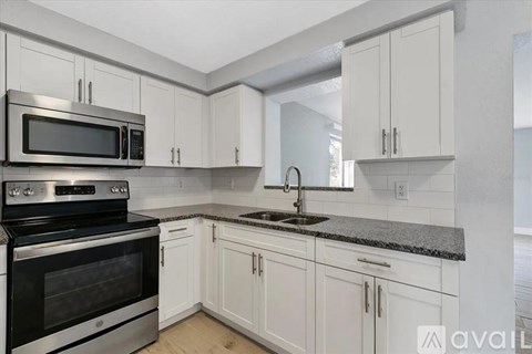 A kitchen with white cabinets and a black stove top oven.