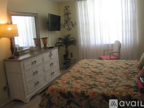 A bedroom with a floral bedspread and a white dresser.