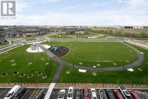 A park area with a playground and a parking lot with cars.