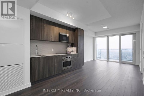 A modern kitchen with dark wood cabinets and white appliances.