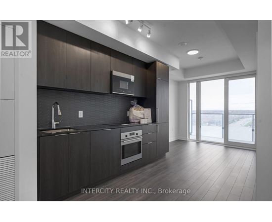 A modern kitchen with dark wood cabinets and stainless steel appliances.