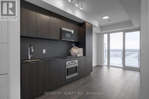 A modern kitchen with dark wood cabinets and stainless steel appliances.