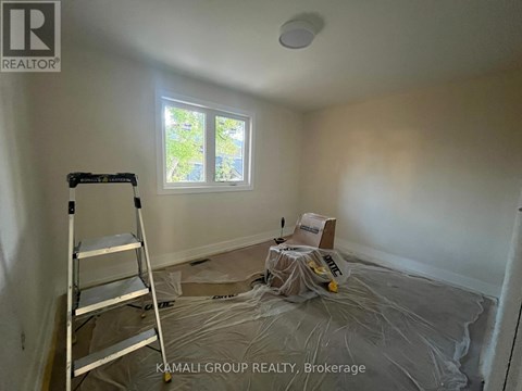A room with a ladder and a window with a view of trees.