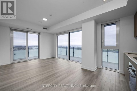A spacious room with wooden flooring and large windows overlooking a snowy landscape.