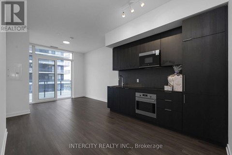 A modern kitchen with black cabinets and a microwave above the stove.