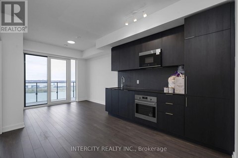 A modern kitchen with dark wood cabinets and a stainless steel oven.