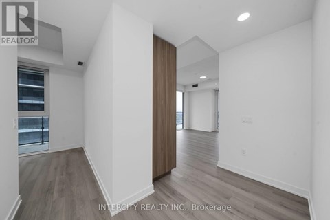 A spacious room with wooden flooring and white walls.