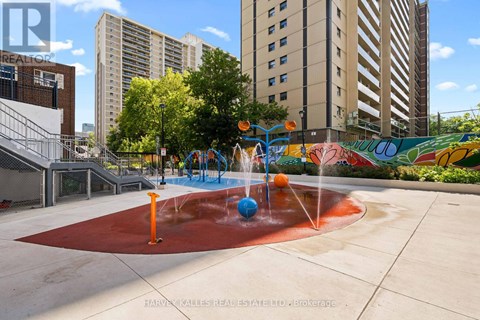 A playground with a red surface and a water feature in the middle.