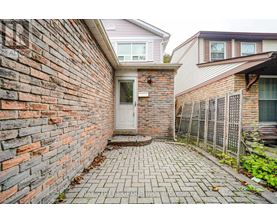 A brick wall with a white door and a brick walkway.
