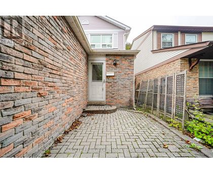 A brick wall with a white door and a brick walkway.
