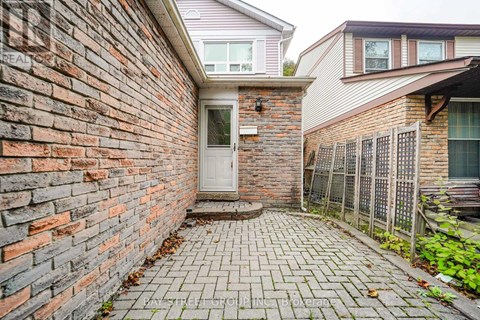 A brick wall with a white door and a brick walkway.