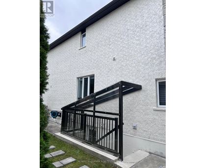 A white house with a black railing on the front porch.