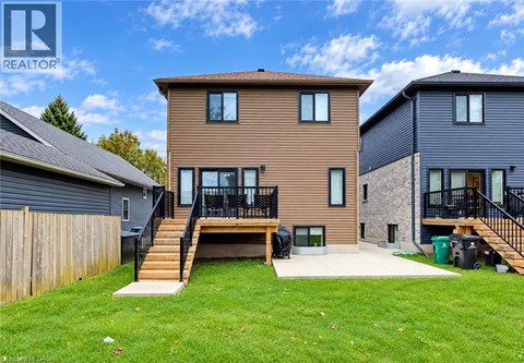 A brown house with a black roof and a green lawn in front.