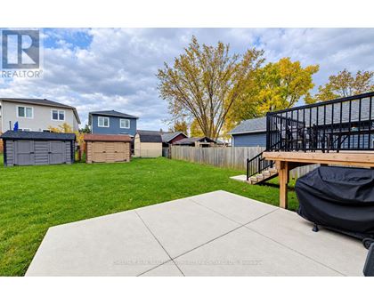 A backyard with a concrete patio and a black grill.