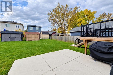 A backyard with a concrete patio and a black grill.
