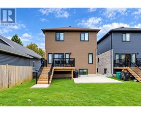 A brown house with a black fence and a green trash can in front.