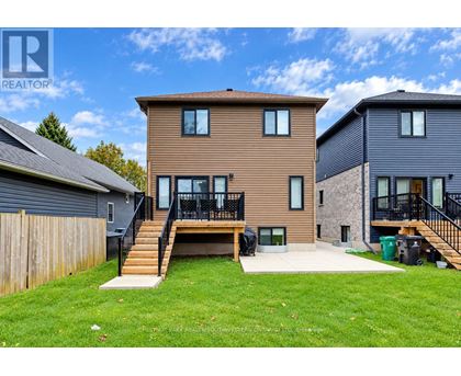 A brown house with a black fence and a green trash can in front.