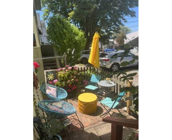 A patio with a yellow umbrella and blue chairs.