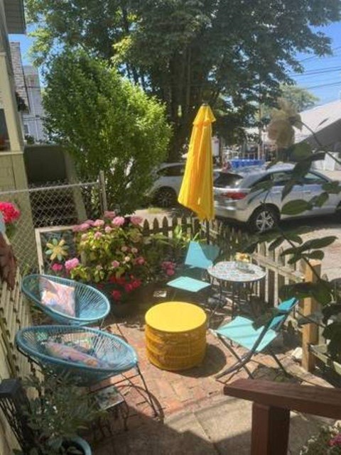 A patio with a yellow umbrella and blue chairs.