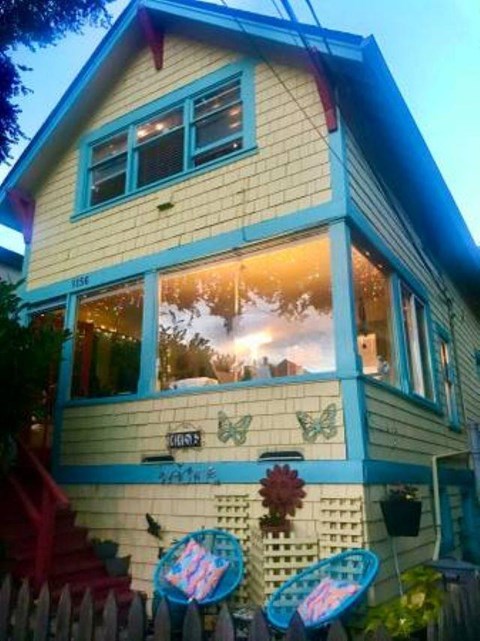 A yellow house with blue trim and a red staircase.