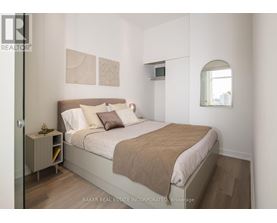 A bedroom with a bed, nightstand, and a window.