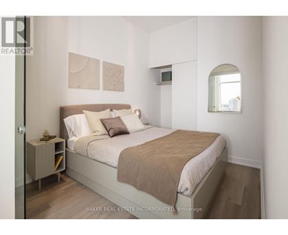 A bedroom with a bed, nightstand, and a window.