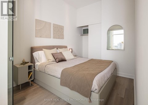 A bedroom with a bed, nightstand, and a window.