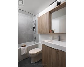 A modern bathroom with a toilet, sink, and a mirror.