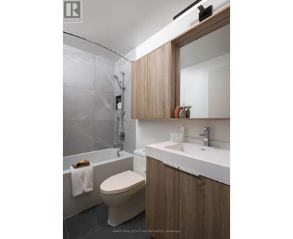 A modern bathroom with a toilet, sink, and a mirror.