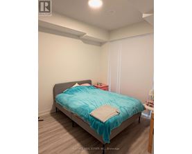 A bedroom with a bed, a nightstand, and a chair.