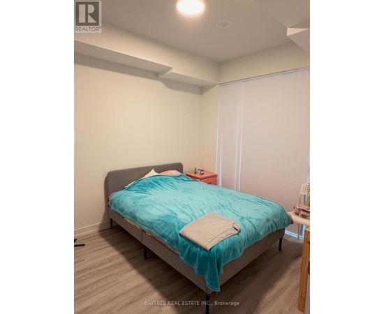 A bedroom with a bed, a nightstand, and a chair.
