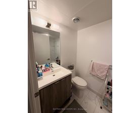 A white sink with a mirror above it and a toilet in the corner.