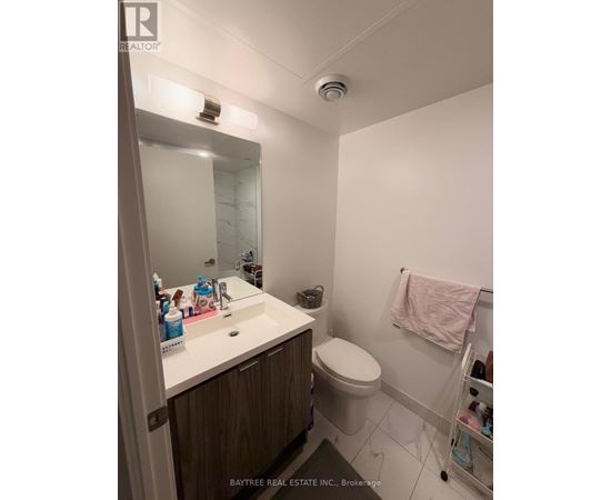 A white sink with a mirror above it and a toilet in the corner.