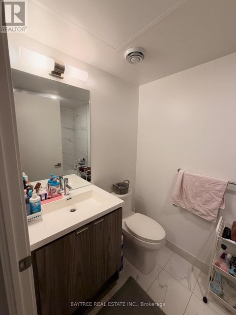 A white sink with a mirror above it and a toilet in the corner.