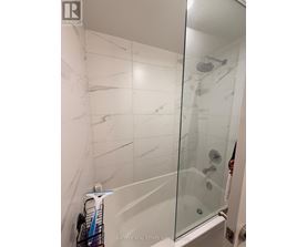 A white tiled shower with a glass door.