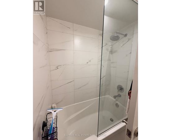 A white tiled shower with a glass door.