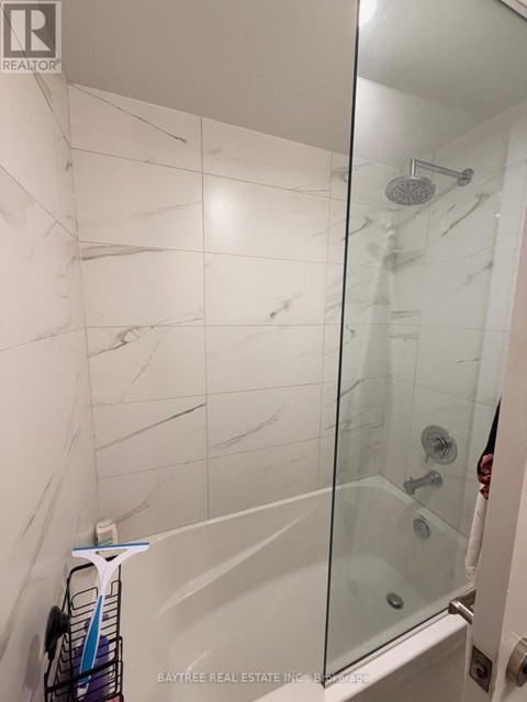 A white tiled shower with a glass door.