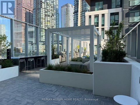 A modern outdoor seating area with a glass wall overlooking a cityscape.