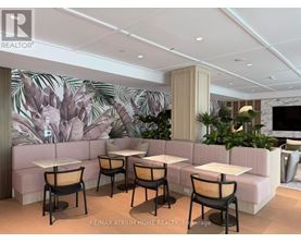 A modern dining area with a large mural of leaves on the wall.