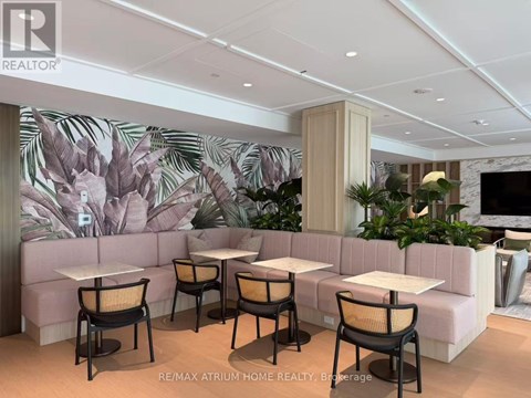 A modern dining area with a large mural of leaves on the wall.