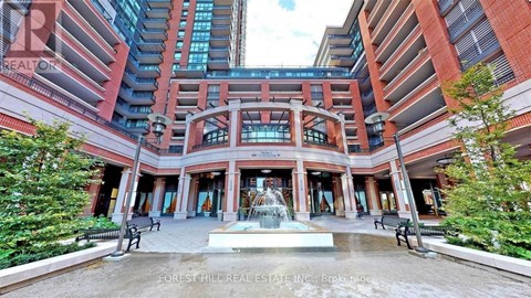A fountain in the middle of a plaza surrounded by benches and trees.