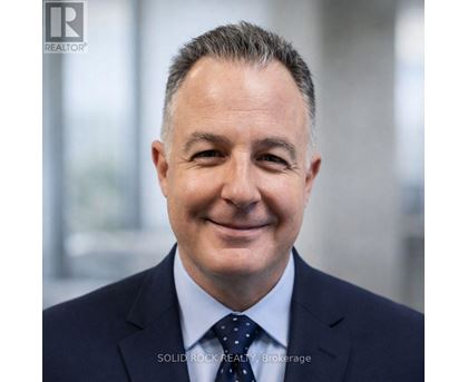 A man in a suit with a dotted tie smiles at the camera.