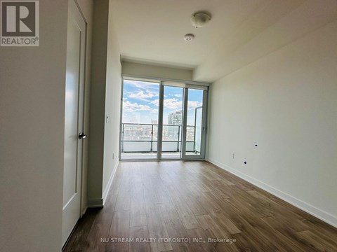A room with wooden floors and a large window with a view of the city.