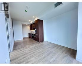 A spacious room with wooden flooring and a kitchenette in the corner.
