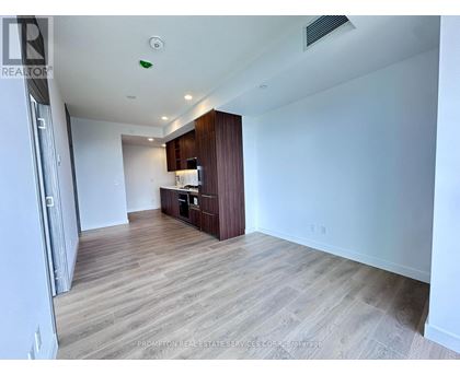 A spacious room with wooden flooring and a kitchenette in the corner.
