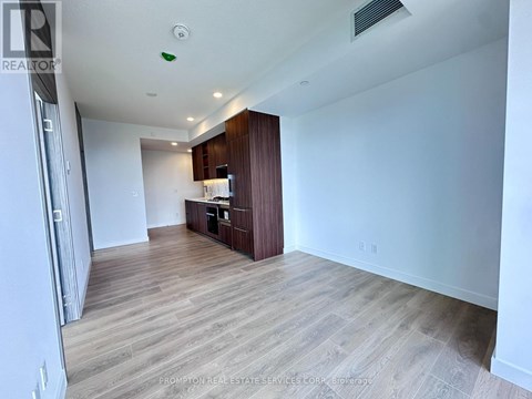 A spacious room with wooden flooring and a kitchenette in the corner.