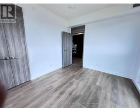 A room with a wooden floor and a white wall with a doorway leading to another room.