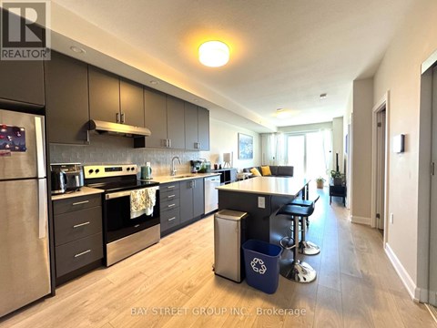 A kitchen with a refrigerator, oven, and bar stools.