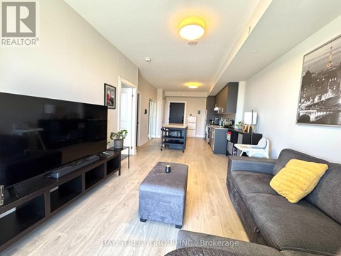 A living room with a grey couch and a black television.
